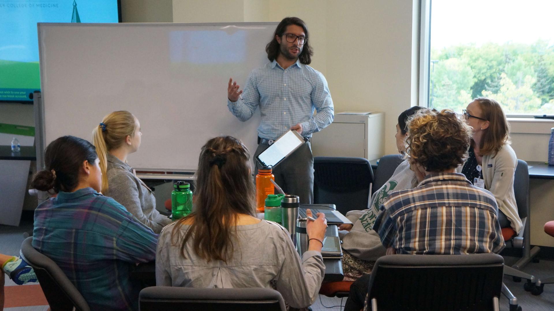 Students gathered around a whiteboard while a Peer Tutor gives a lecture