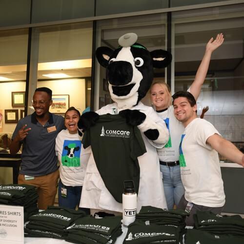 group of students have fun with a person in cow costume