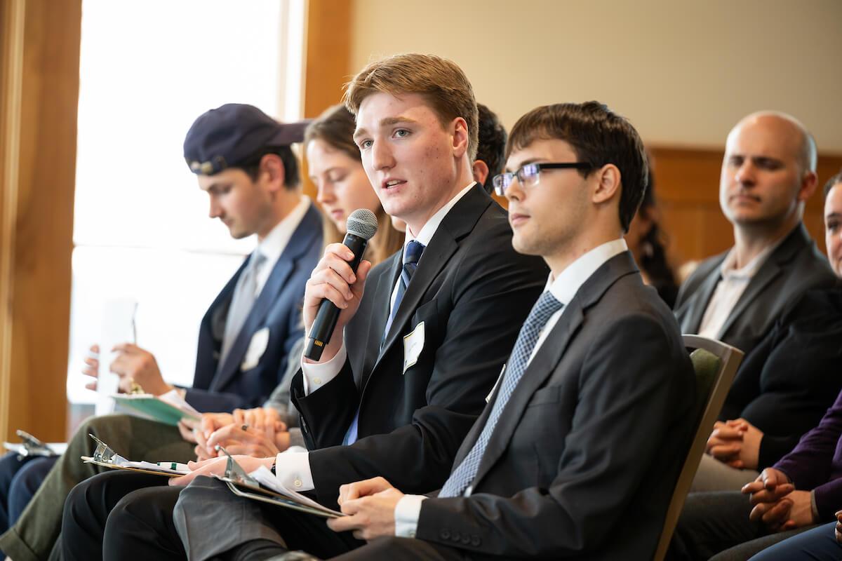 Students wearing business suits watch pitches 