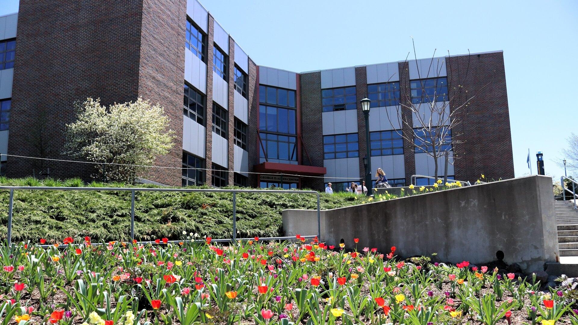 A view of the Aiken Center building with a garden of tulips and a blooming tree in front of the building