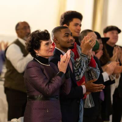 Provost Prelock, two student leaders from Mosaic Center, and others blurred in the background giving a standing ovation.