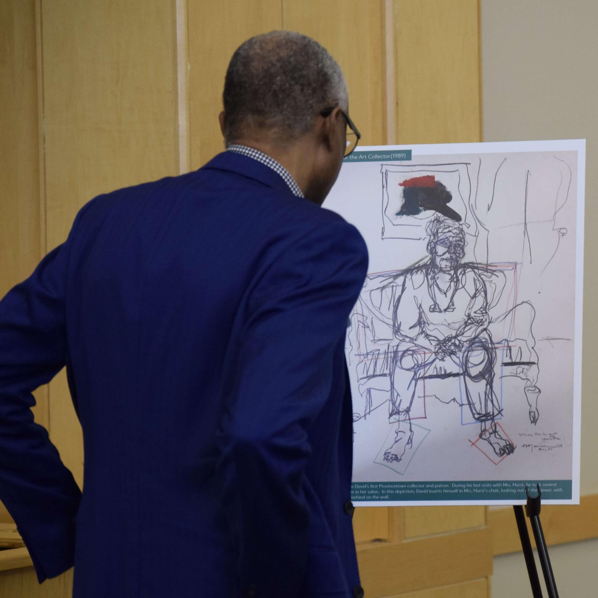 Man looking at a print of a sketch done by Jamieson