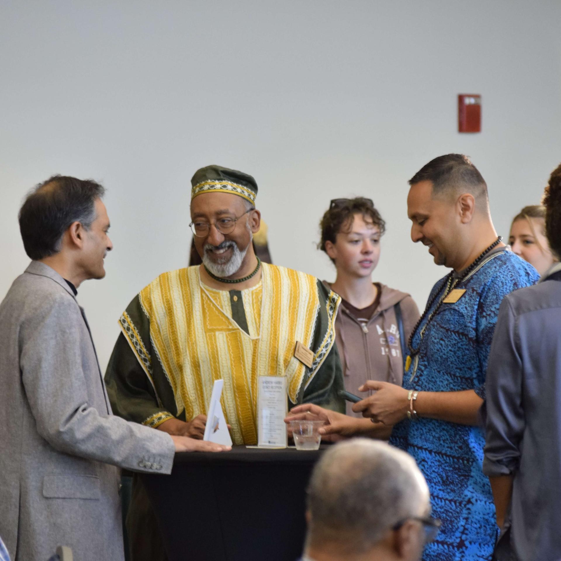 President Garimella, Dr. Sherwood Smith, and Vice Provost Amer Ahmed smile and laugh while standing around a hightop table