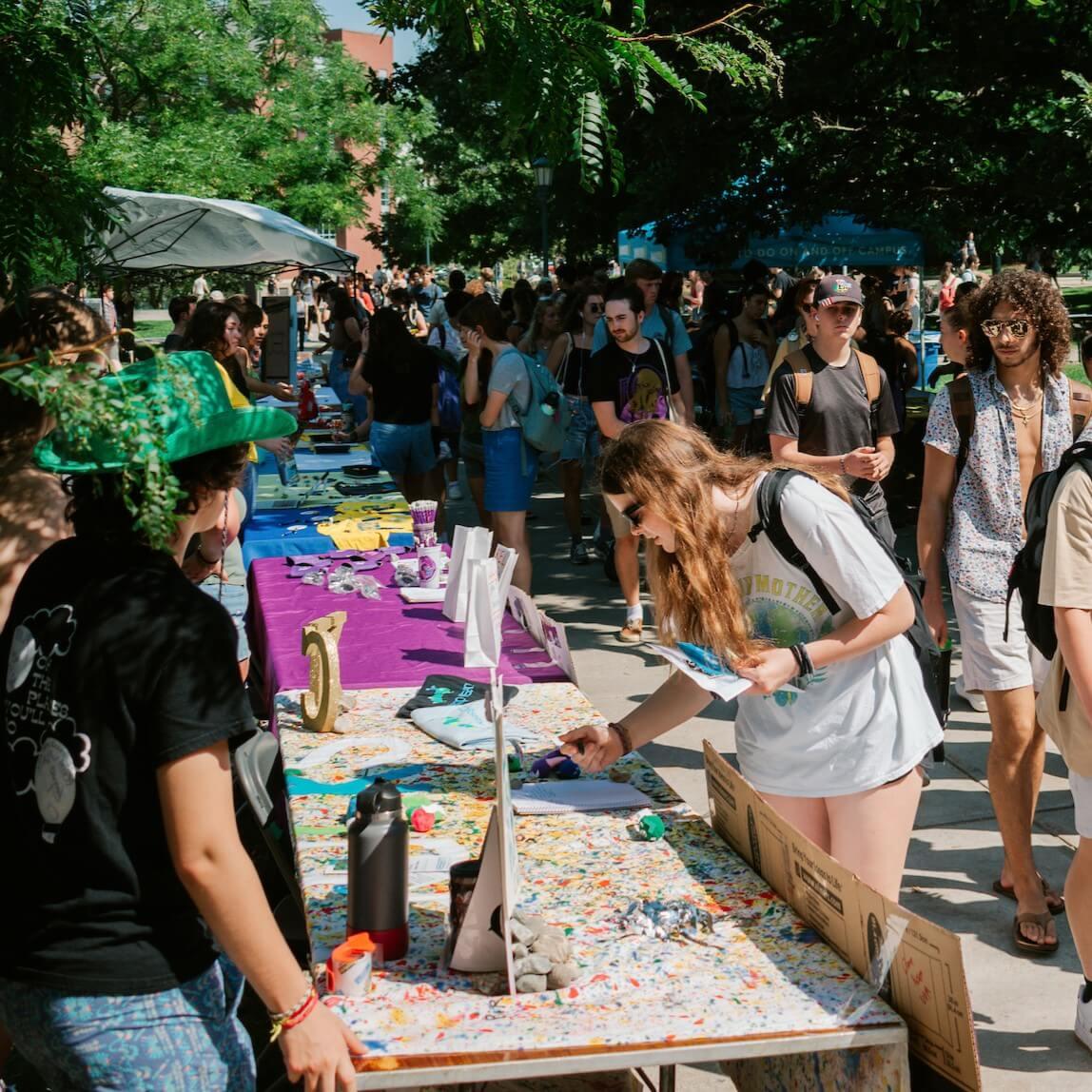 Students on campus walking to different club tables during activity fest.