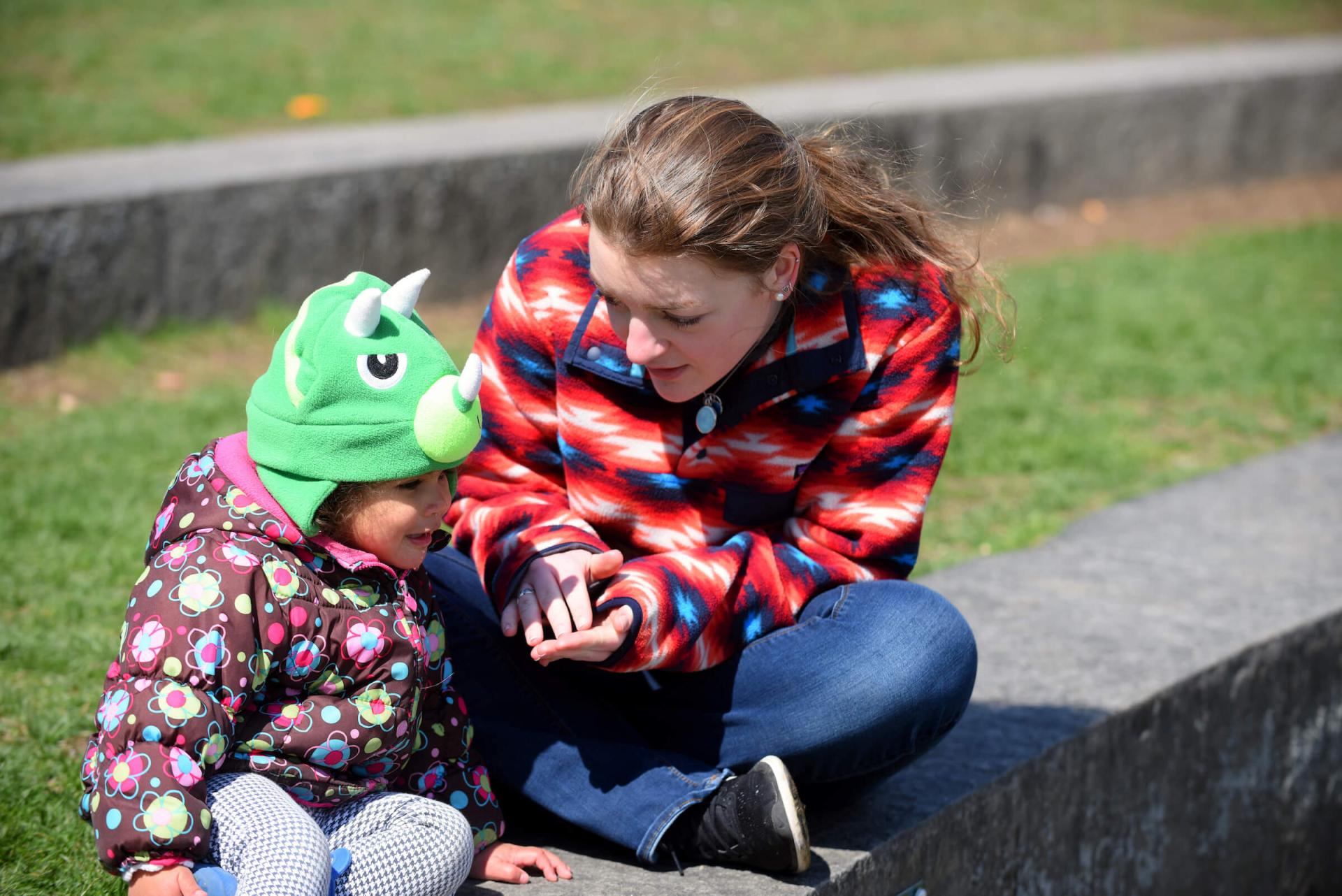 Student teacher engages with a young child during outdoor exploration time.