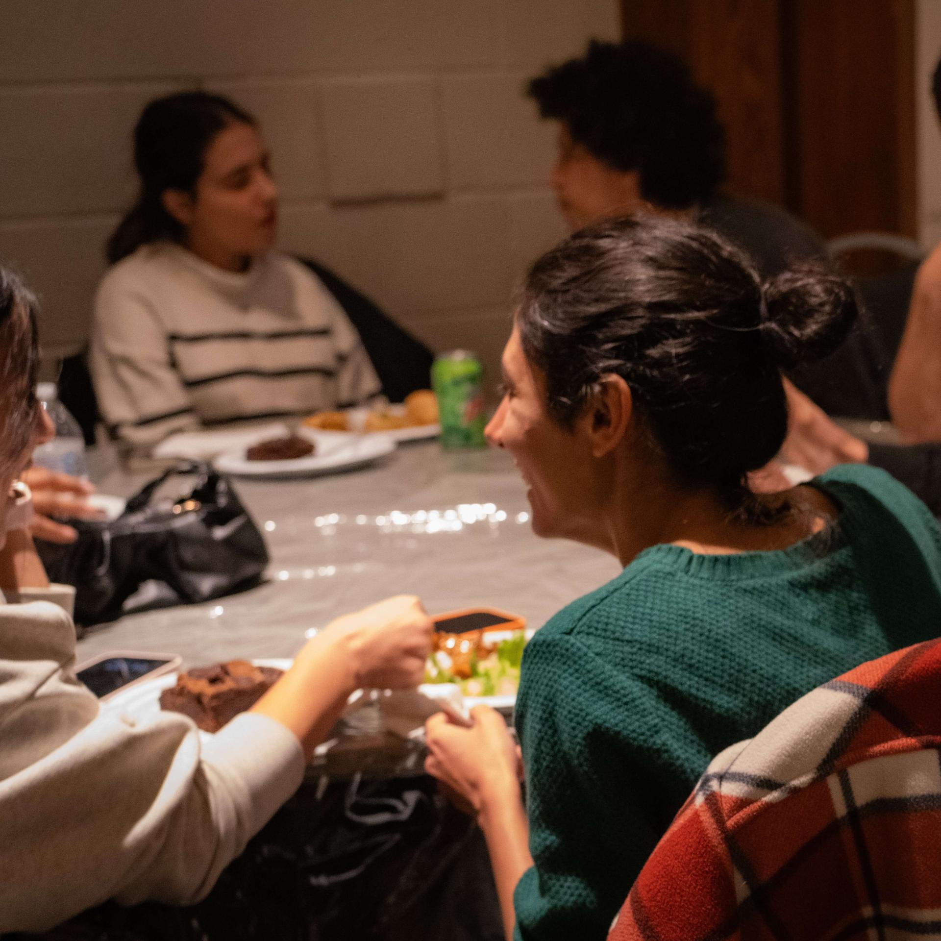 People engage in conversation around a table at the Interfaith Center