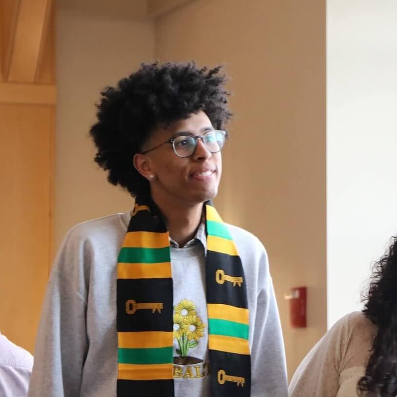 Student receiving Kente stole and glasses smiles at MCSC Graduation Brunch