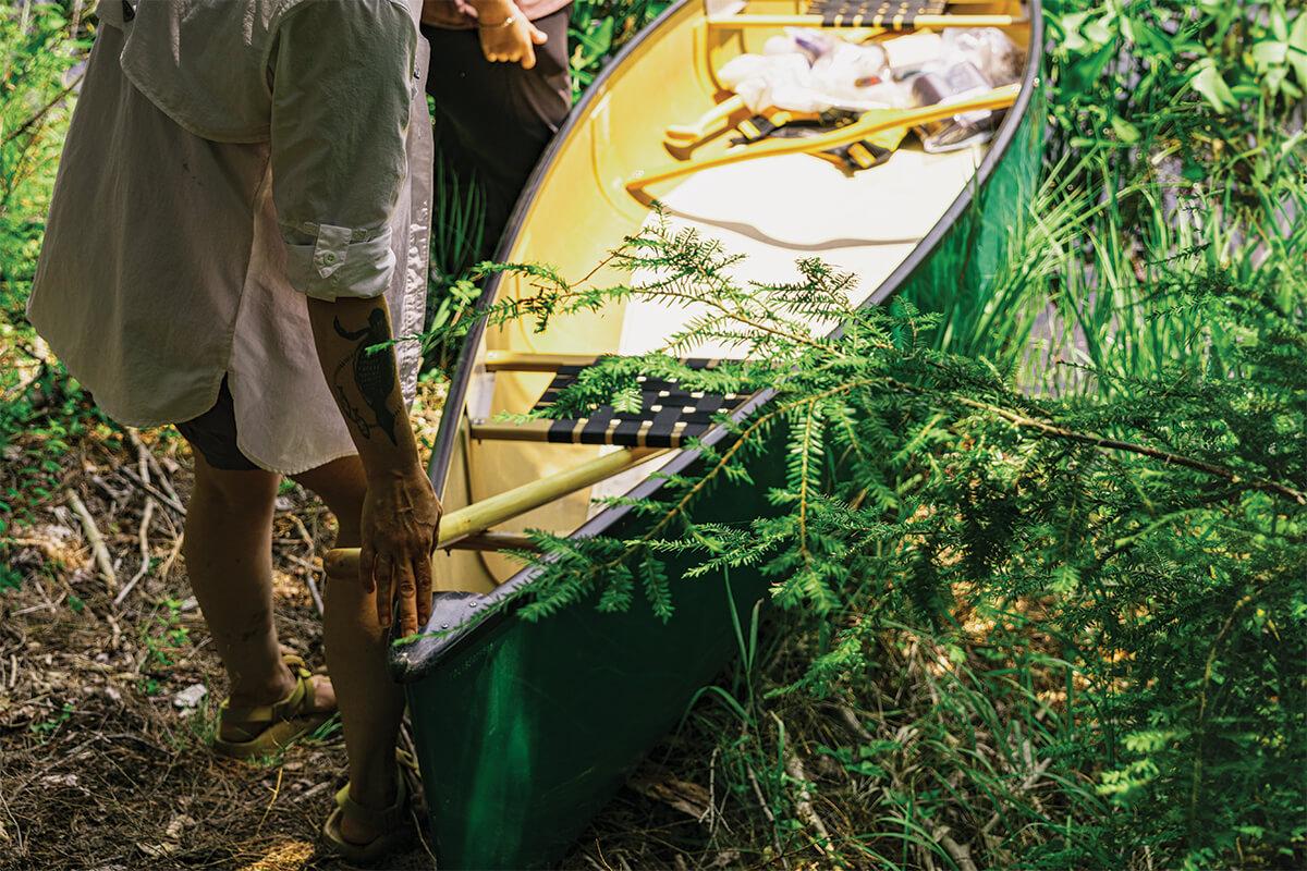 Two researchers loading a canoe into a pond