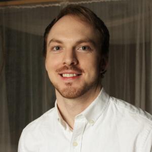 Kevin, smiling, in a darker, indoor setting