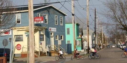 Group of people on bikes, pedaling down a street on a sunny day