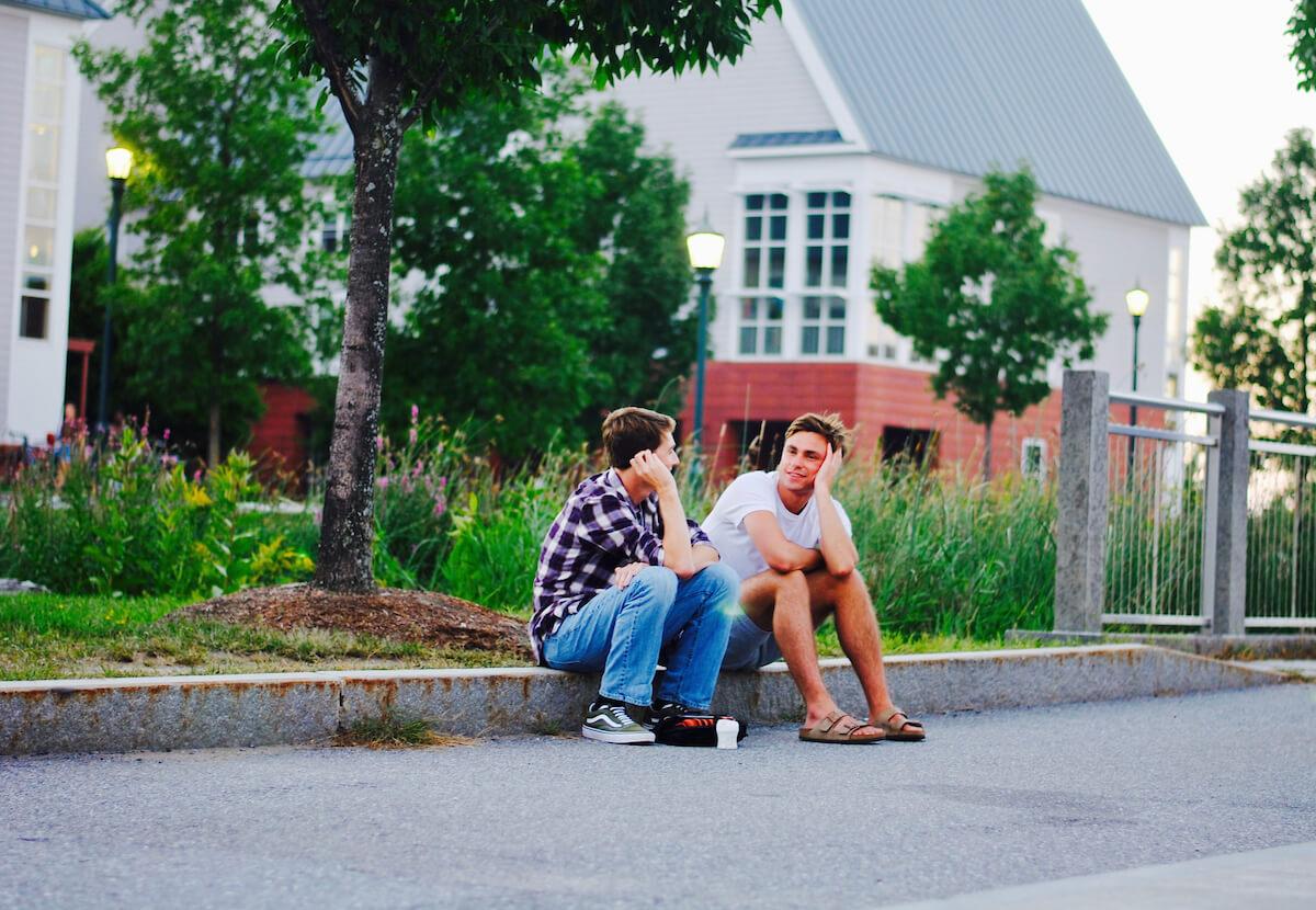 Two students sitting and chatting in front of student housing. 