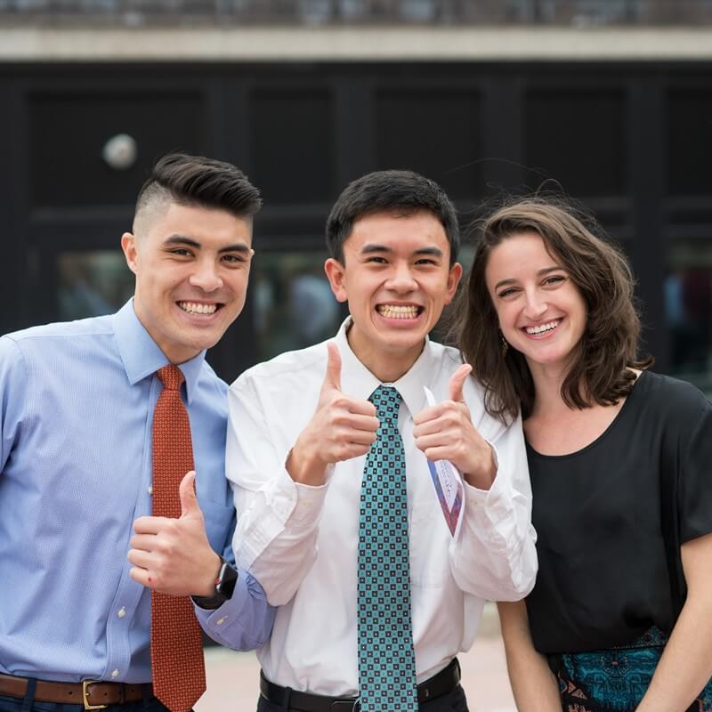 three students giving a thumbs up