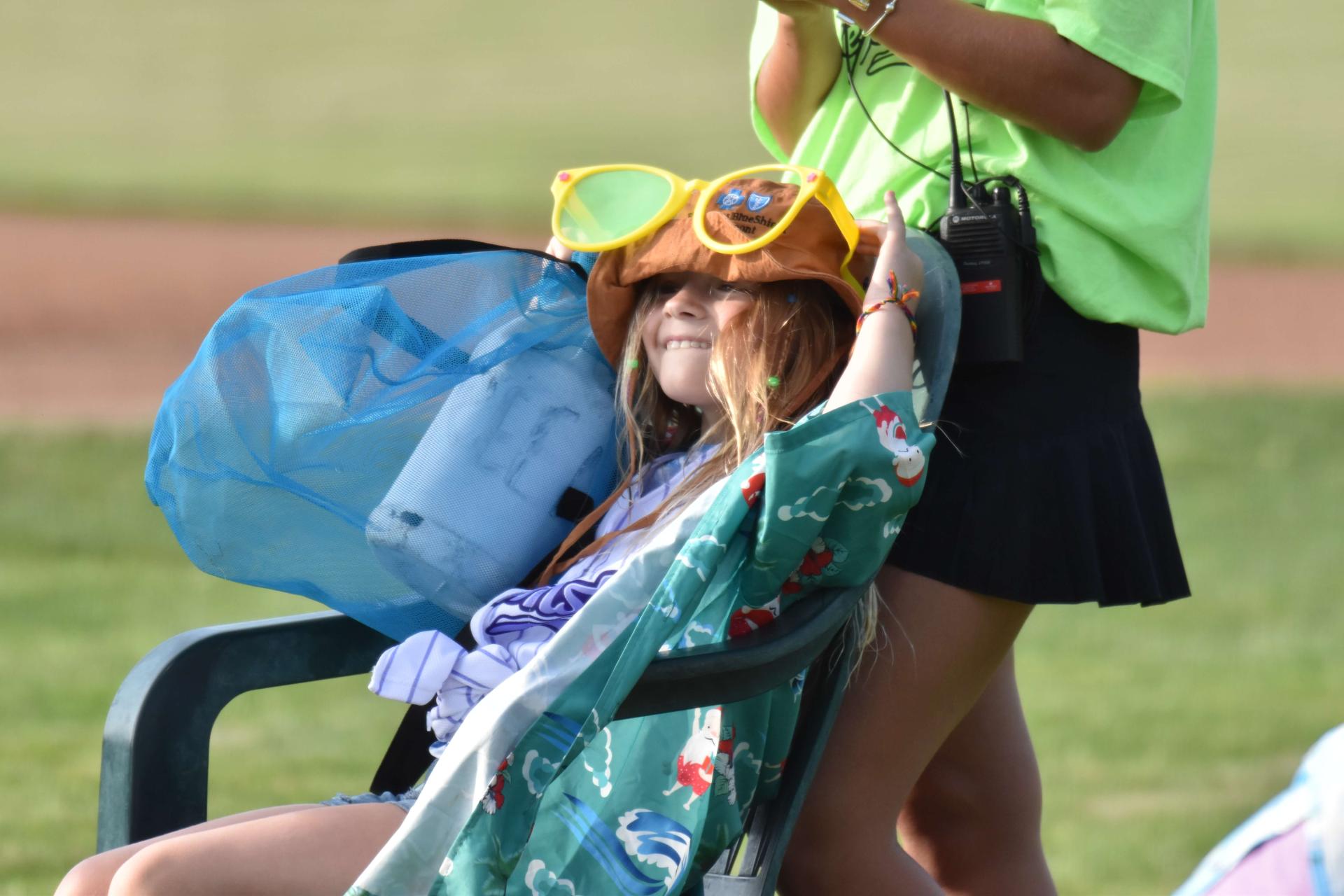 Girl in chair at Lake Monsters game wears hat, sunglasses, and shirt to illustrate sun safety tips.