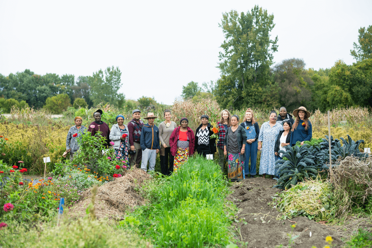 Students work with new farmers and stand together in a field
