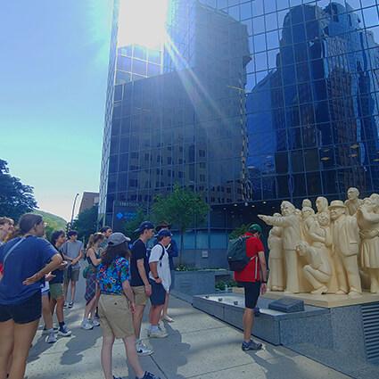 A group of students looking at a statue setup.