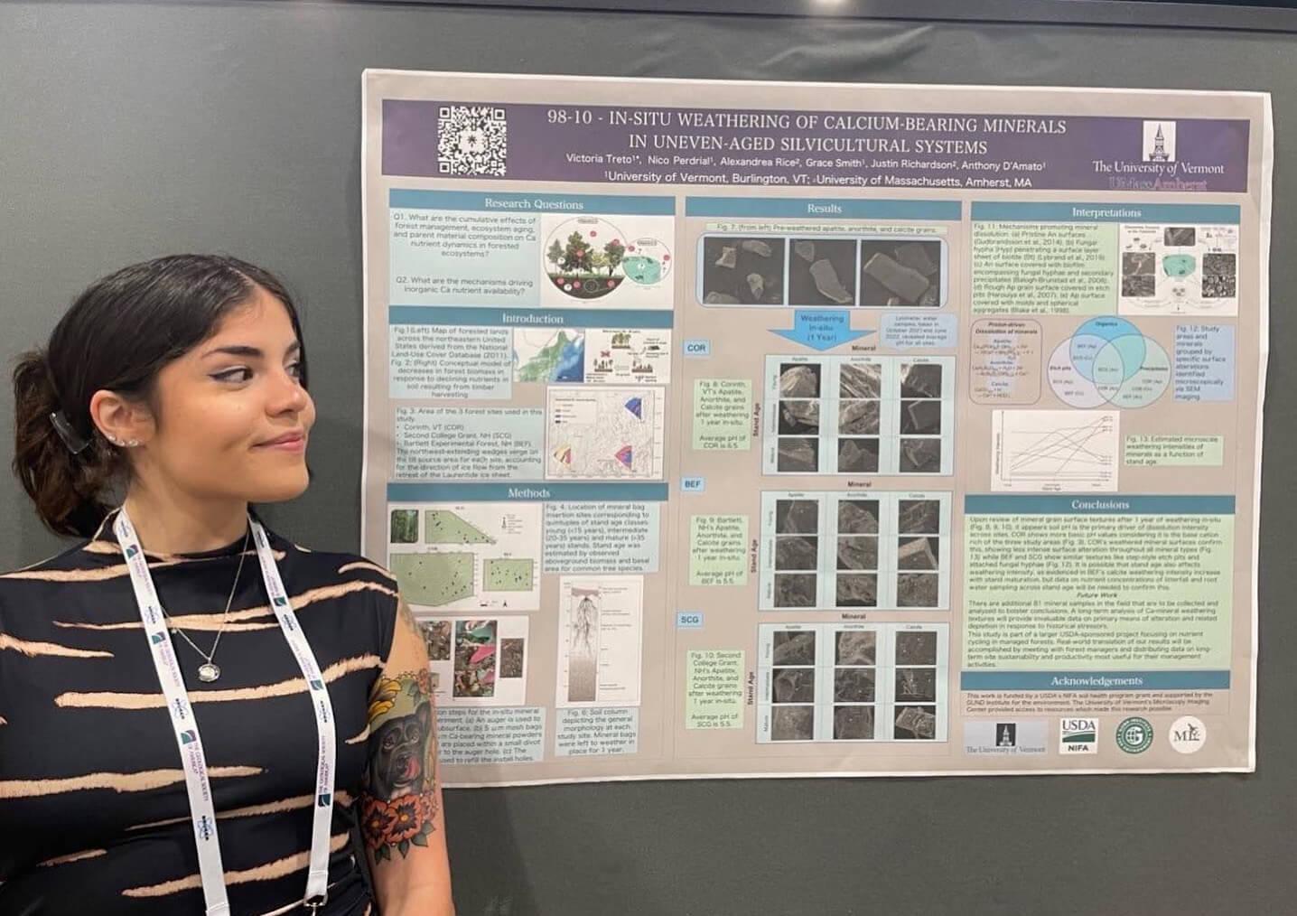 Student stands beside a research poster