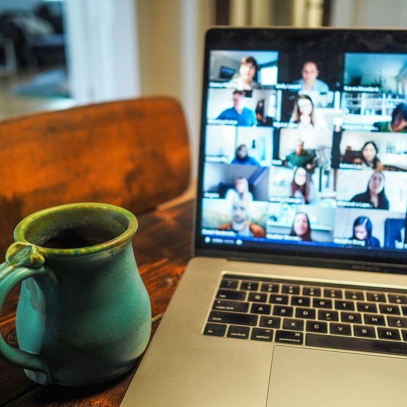 A coffee mug next to a laptop with a virtual meeting on the screen. Photo by Chris Montgomery.