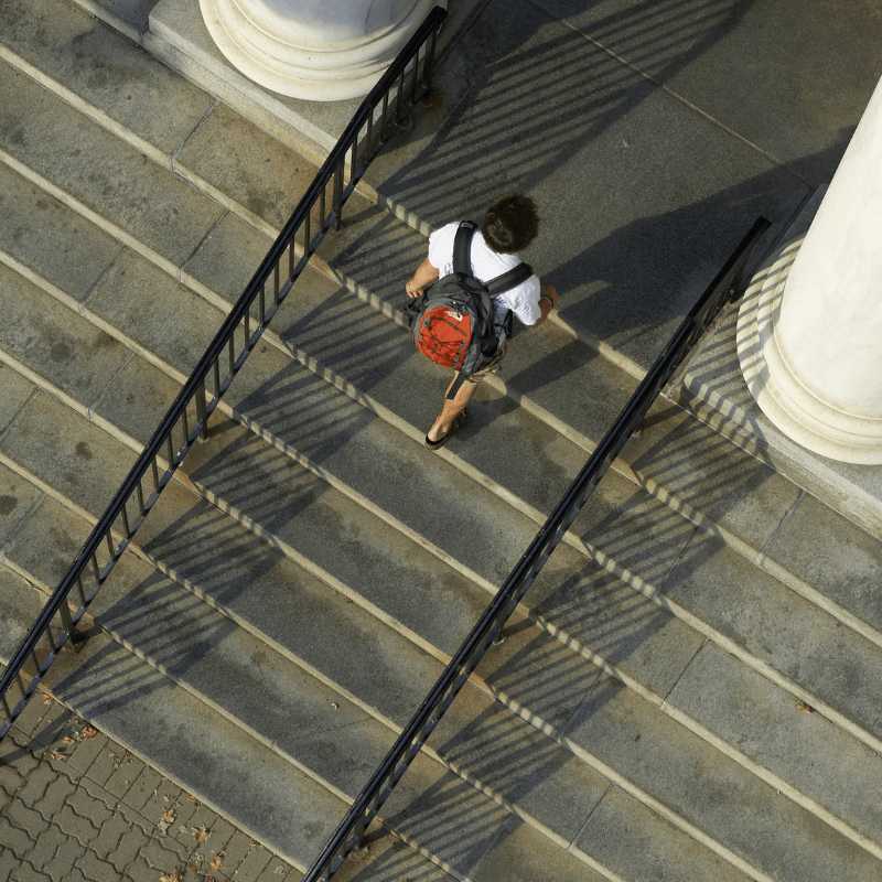 person wearing a backpack ascending a staircase