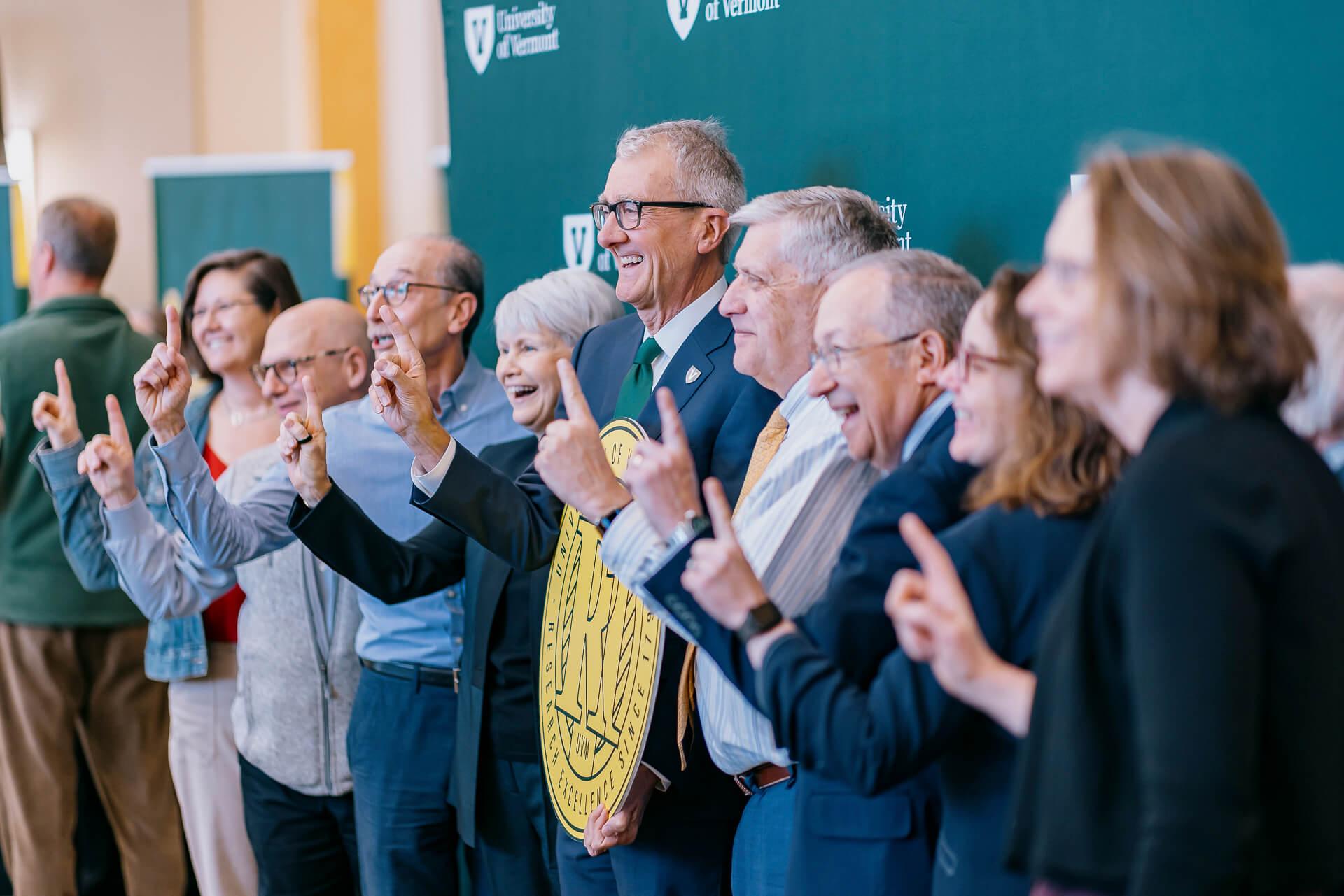A group of people hold an R1 sign above a green background