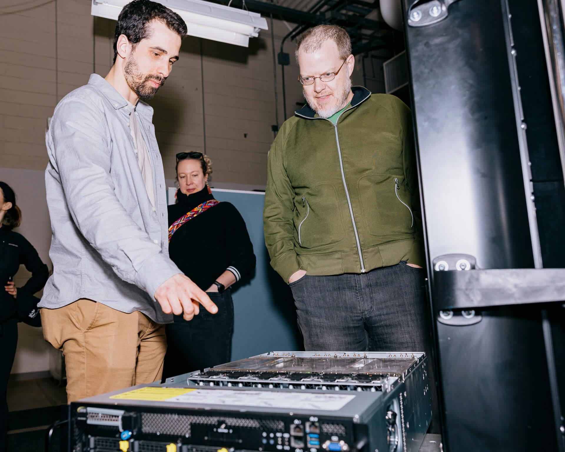 Two people examine a computer server