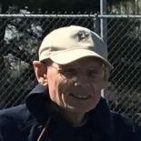 Bespeckled man wearing a baseball cap in an outdoor setting
