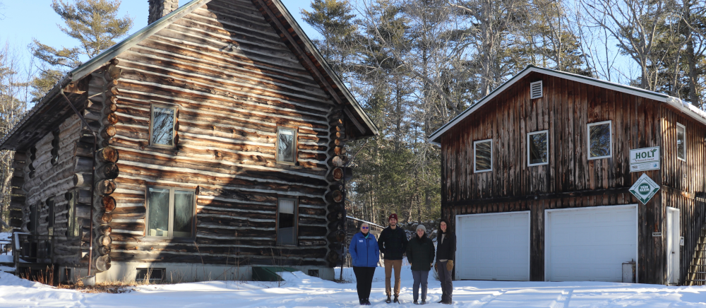 Photo of four people outside the snow covered Holt research station buildings in winter.