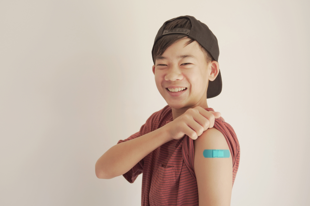 boy showing a blue bandaid after a flu vaccine