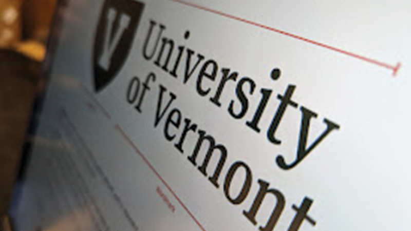 angled photo of a computer screen with the University of Vermont logo: A white letter V outlined by a dark green shield and the text University of Vermont
