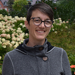 Kate standing in front of white flowers wearing a grey sweater