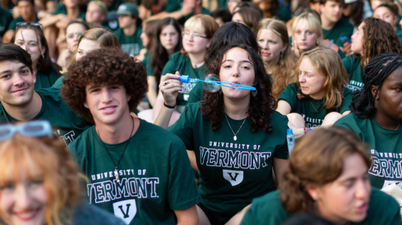 Woman wearing green shirt blows bubbles in a large group