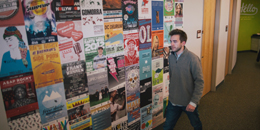 a student walks by a wall of posters in the department of student life