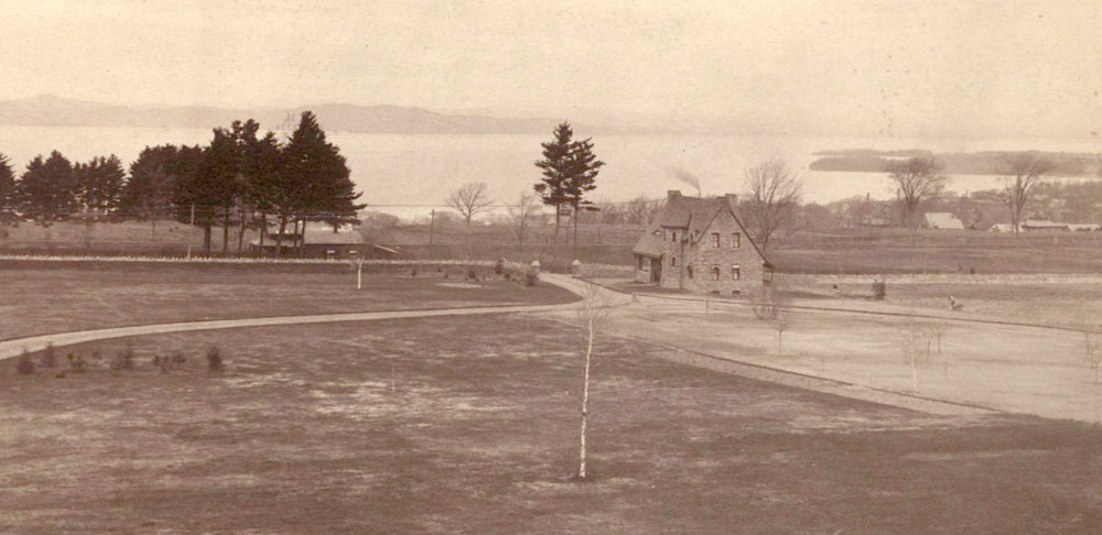 Picture of the Redstone Lawn, Gatehouse and wall with Lake Champlain in the background.